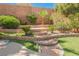Lush backyard featuring multi-tiered landscaping, a stone pathway and artificial turf at 209 Camino Vista St, Henderson, NV 89012