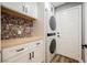 Well-organized laundry room with white cabinets, wooden countertop, mosaic tile backsplash, and stacked washer/dryer at 209 Camino Vista St, Henderson, NV 89012