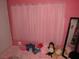Bright pink bedroom featuring a full length mirror, window with pink curtains and a selection of plush toys at 2409 Maroney Ave, Las Vegas, NV 89104