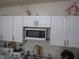 Clean kitchen with white cabinets, a microwave, and a sink area with standard appliances at 2409 Maroney Ave, Las Vegas, NV 89104