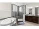 Luxurious bathroom featuring a soaking tub, walk-in shower, granite countertops, and dark wood cabinets at 245 Hull St, Henderson, NV 89015