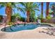 Backyard pool features mature palm trees, a stone waterfall, and a basketball hoop for entertainment at 2500 Wimbledon Dr, Las Vegas, NV 89107