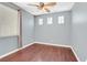 Bright bedroom featuring hardwood floors, three windows, a ceiling fan, and light gray wall paint at 2864 Kinknockie Way, Henderson, NV 89044