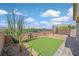 Landscaped backyard with artificial grass, mature desert vegetation, pergola, and brick paved patio at 3096 Beaux Art Ave, Henderson, NV 89044