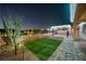 Beautiful backyard at night with artificial turf, desert plants, and paver patio at 3096 Beaux Art Ave, Henderson, NV 89044