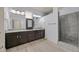 This bathroom features granite countertops, dark cabinets, dual sinks, and a shower with light hardwood floors at 3096 Beaux Art Ave, Henderson, NV 89044