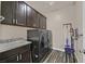 Laundry room with dark cabinets, sink, counter space, striped flooring, and high-end washer and dryer at 3096 Beaux Art Ave, Henderson, NV 89044