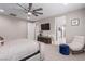 This primary bedroom offers a ceiling fan, TV, and cozy seating area with a plush ottoman and decorative chair at 3929 Reyes Ave, Las Vegas, NV 89141