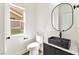 Modern bathroom featuring toilet, decorative black sink with round mirror, and a window at 4779 Straight Flush Dr # 103, Las Vegas, NV 89122