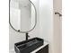 Stylish bathroom featuring a modern black sink, round mirror and white walls at 4779 Straight Flush Dr # 103, Las Vegas, NV 89122