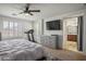 Bright primary bedroom featuring a ceiling fan, dresser, treadmill and an attached bathroom at 4786 Castel Martini Ct, Las Vegas, NV 89147