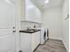 Well-equipped laundry room with white cabinets, sink, and modern washer and dryer at 5500 Santovito St, Pahrump, NV 89061