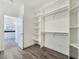 Bright walk-in closet with white shelving and wood-look floors, with a glimpse into the adjacent kitchen at 5500 Santovito St, Pahrump, NV 89061