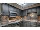 Well-lit kitchen featuring sleek black cabinetry, stainless steel microwave, and a modern backsplash at 6463 Big Pine Way, Las Vegas, NV 89108