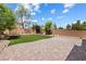 A spacious backyard featuring a pristine lawn, mature trees, and a brick-paved patio area for outdoor relaxation at 6783 Pleasant Flower St, Las Vegas, NV 89149