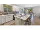 Bright kitchen with white cabinets, stainless steel appliances, mosaic backsplash, an island with barstool seating and sliding door at 6783 Pleasant Flower St, Las Vegas, NV 89149
