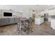 Open-concept living room with grey sofa, ceiling fan, hardwood floors, dining area, and white kitchen with stainless steel appliances at 6783 Pleasant Flower St, Las Vegas, NV 89149