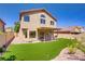 Home's backyard featuring manicured lawn, covered patio, and desert landscaping at 7813 Paper Flower Ct, Las Vegas, NV 89128