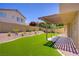 Landscaped backyard with artificial turf, covered patio and mature trees at 7813 Paper Flower Ct, Las Vegas, NV 89128