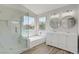 Modern bathroom with double vanity, walk in shower and soaking tub under a large window at 7813 Paper Flower Ct, Las Vegas, NV 89128