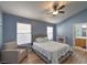 Bedroom with blue walls, wood floors, ceiling fan, windows, and sitting chair at 8109 Sunset Mill Dr, Las Vegas, NV 89128
