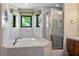 Bright bathroom featuring a corner tub, tiled walls, and a glass-enclosed shower at 8365 S Hauck St, Las Vegas, NV 89139