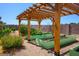 Landscaped backyard featuring a wooden pergola and several raised garden beds at 8365 S Hauck St, Las Vegas, NV 89139
