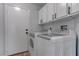 This laundry room features white cabinets, matte black hardware, and a pair of modern white appliances at 887 Cozy Valley St, Henderson, NV 89015