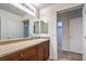 Bright bathroom with a vanity with granite countertop, large mirror, wood-look flooring, and convenient access to closet at 10085 S Riley St, Las Vegas, NV 89178