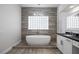 Bathroom featuring a soaking tub, wood-style accent wall, and glass block window at 10113 Plomosa Pl, Las Vegas, NV 89134