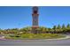 View of a community clock tower surrounded by circular landscaping and mature trees at 11441 Drappo Ave, Las Vegas, NV 89138