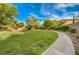 A well-maintained community green space featuring lush grass, mature trees, and sidewalks at 11441 Drappo Ave, Las Vegas, NV 89138