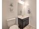 Small powder room with a white toilet, a dark vanity, a sink and art on the wall at 12286 Silvana St, Las Vegas, NV 89141