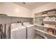 A laundry room with washer, dryer and built in storage shelves for convenience at 12286 Silvana St, Las Vegas, NV 89141