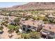 An aerial view captures the house and the surrounding neighborhood nestled against a mountain range and golf course at 2436 Grassy Spring Pl, Las Vegas, NV 89135
