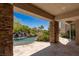 Tranquil covered patio with stone accents overlooking a pool and waterfall feature at 2436 Grassy Spring Pl, Las Vegas, NV 89135