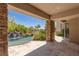 Inviting covered patio with stone accents, offering serene views of the pool and waterfall at 2436 Grassy Spring Pl, Las Vegas, NV 89135