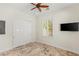 Well-lit room featuring travertine floors, closet, mounted TV and window with white shutters at 2436 Grassy Spring Pl, Las Vegas, NV 89135