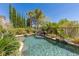 Sparkling pool surrounded by lush greenery and a rock waterfall, creating a serene oasis at 2436 Grassy Spring Pl, Las Vegas, NV 89135