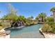 Beautiful pool with a rock waterfall feature surrounded by lush landscaping at 2436 Grassy Spring Pl, Las Vegas, NV 89135