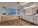 Luxurious bathroom with a soaking tub surrounded by tile and windows for natural light and dual sinks at 2448 Ram Crossing Way, Henderson, NV 89074