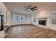 Living room featuring wood floors, bright windows, modern ceiling fan, and cozy fireplace at 2448 Ram Crossing Way, Henderson, NV 89074