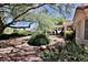 Landscaped backyard featuring a covered patio, water feature, and mature trees at 2820 Bluff Point Dr, Las Vegas, NV 89134