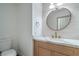 Bathroom featuring a wood vanity with marble countertop, round mirror and modern fixtures at 3020 Via Venezia, Henderson, NV 89052