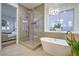 Modern bathroom featuring a glass shower, soaking tub, gold accents and stylish chandelier lighting at 3020 Via Venezia, Henderson, NV 89052