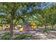 Colorful playground with slides, climbing structures, and a soft surface, nestled among mature shade trees and green grass at 3020 Via Venezia, Henderson, NV 89052