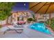 Luxury backyard featuring a pool, lounge chairs, covered patio, palm trees, and an outdoor living space at 3050 Whispering Crest Dr, Henderson, NV 89052
