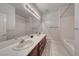 A bright bathroom featuring double sinks, a large mirror, and a bathtub with shower at 3050 Whispering Crest Dr, Henderson, NV 89052
