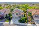 Charming two-story home with a well-manicured lawn, mature trees, and solar panels on the roof at 3050 Whispering Crest Dr, Henderson, NV 89052