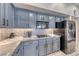 Kitchen boasts stainless steel appliances, granite countertops and blue painted cabinets at 3050 Whispering Crest Dr, Henderson, NV 89052